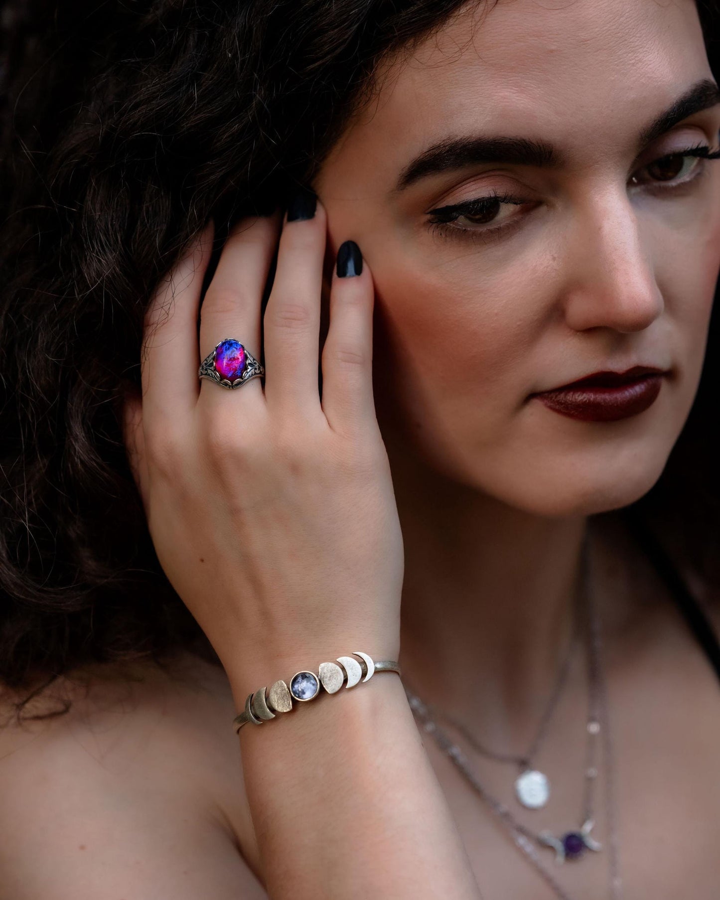 Woman wearing a ring and moon phase bracelet with a blurred background