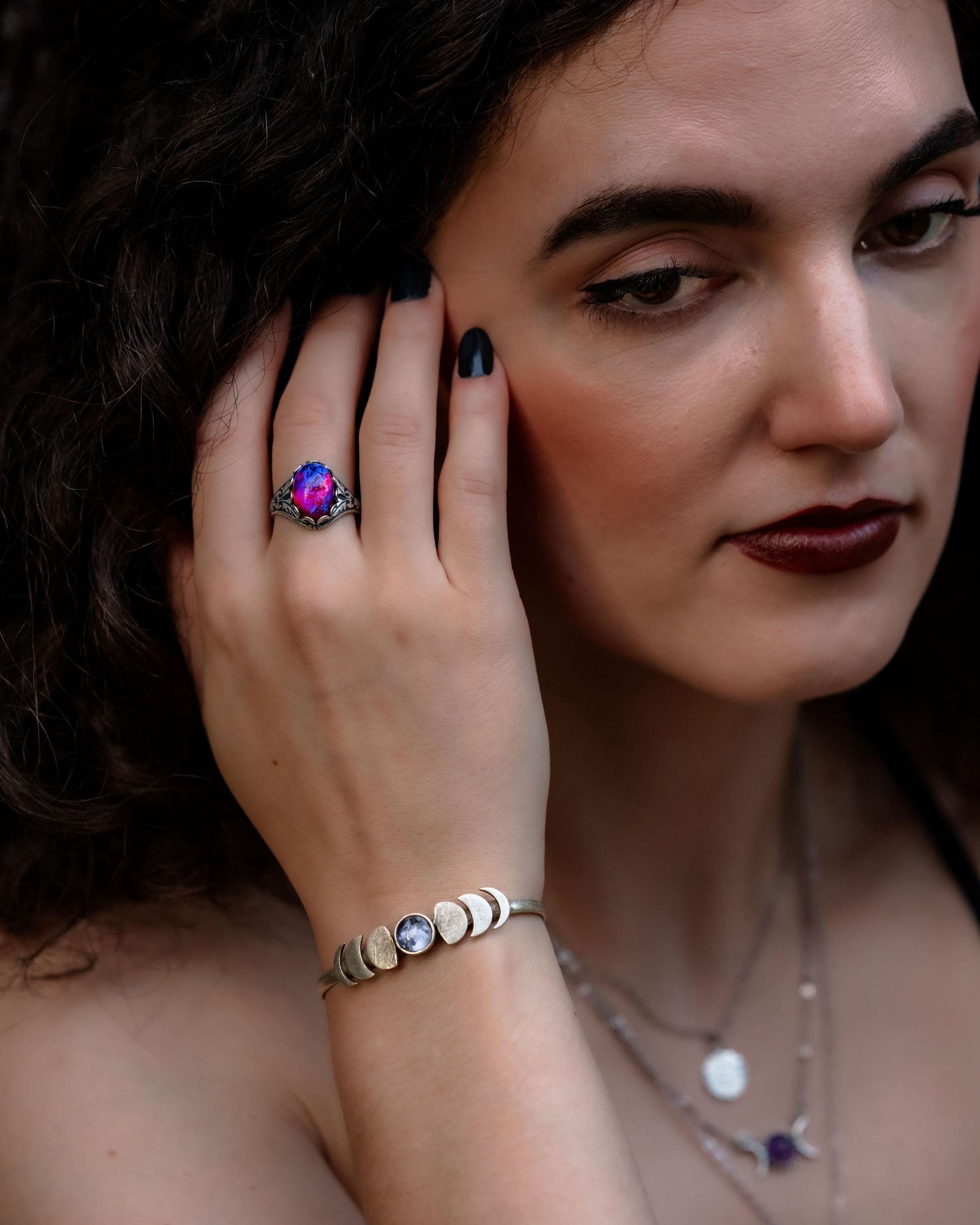 Woman wearing a ring and moon phase bracelet with a blurred background