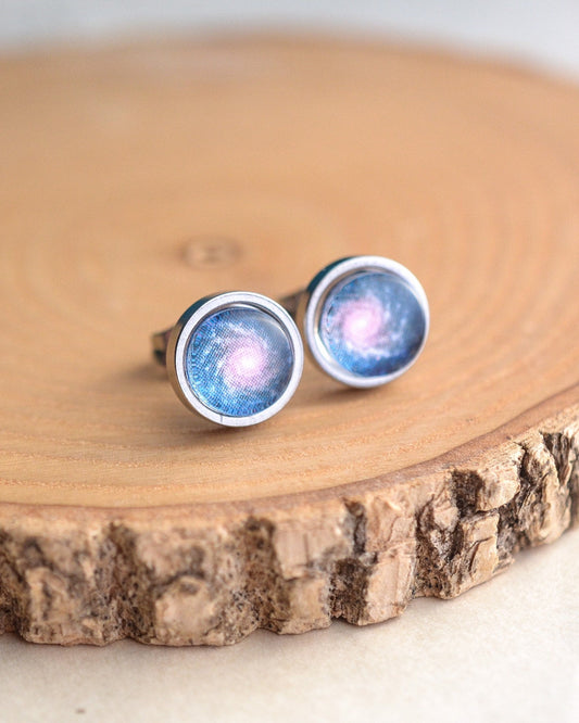 Pair of galaxy-themed stud earrings on a wooden surface