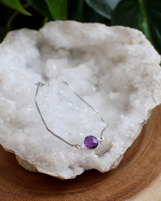 Purple stone silver bracelet laying on a white geode