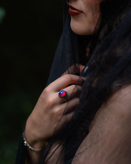 Person wearing a dark scarf  and red stone ring with a blurred background