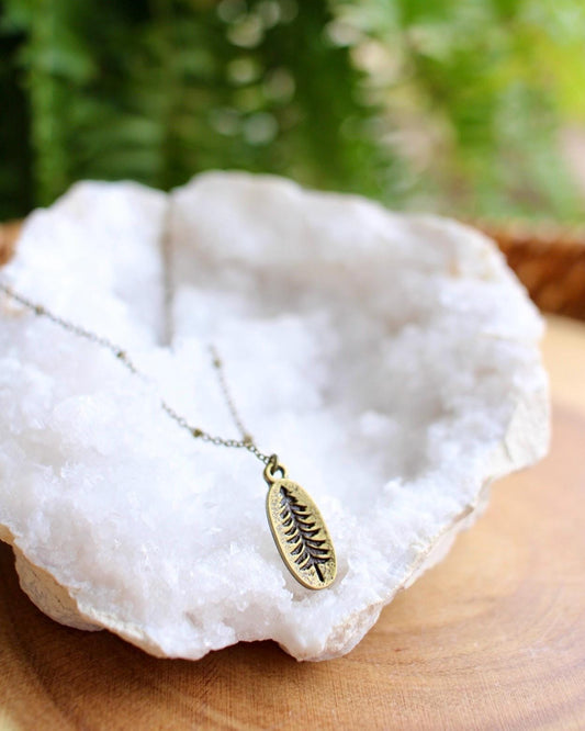 Necklace with a tree pendant on a white stone with green foliage in the background