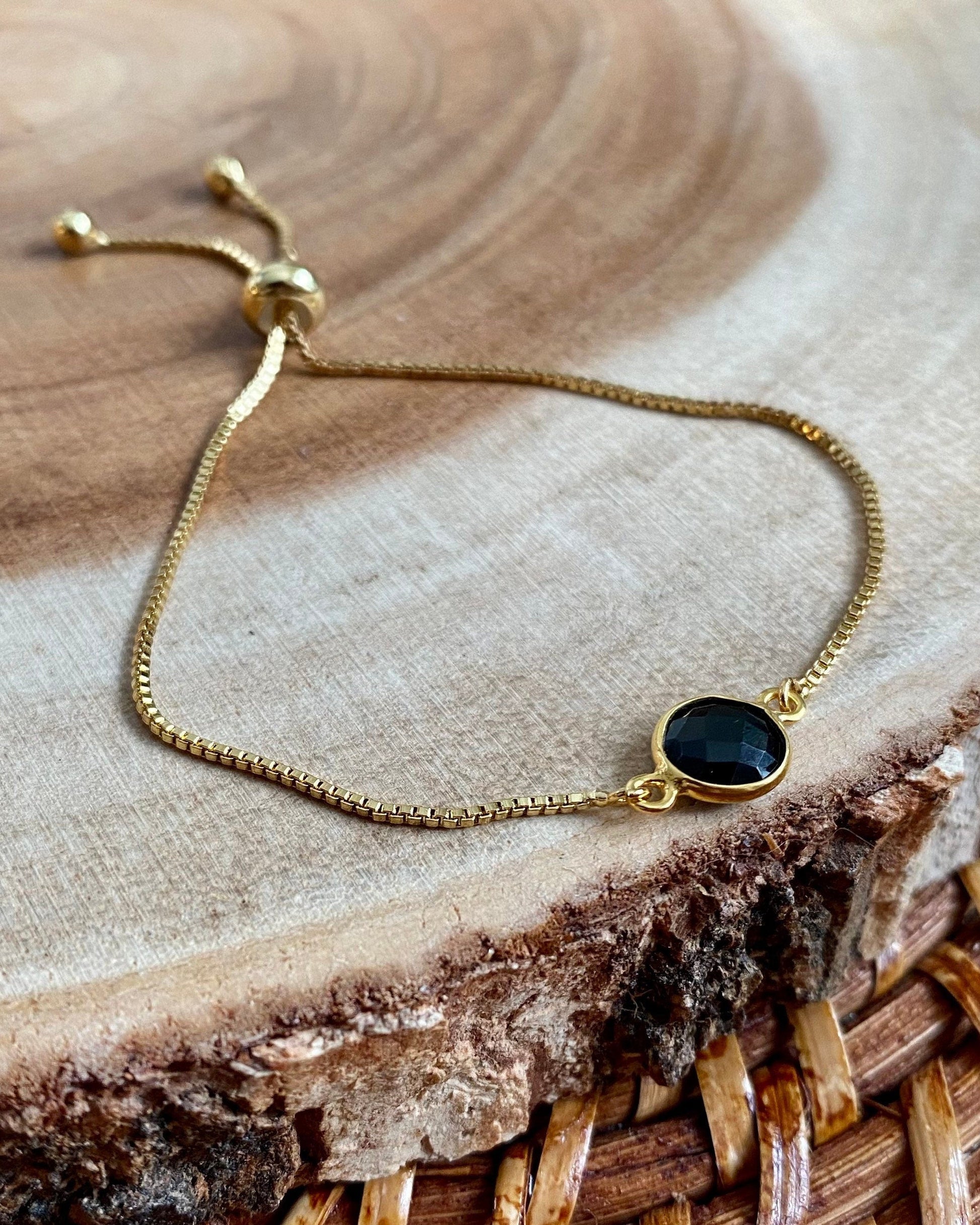 Gold bracelet with a black stone on a wooden surface