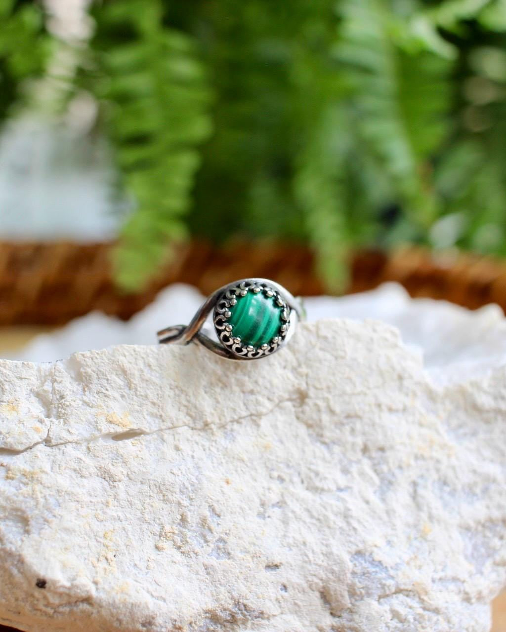Green stone ring on top of a white crystal with greenery background