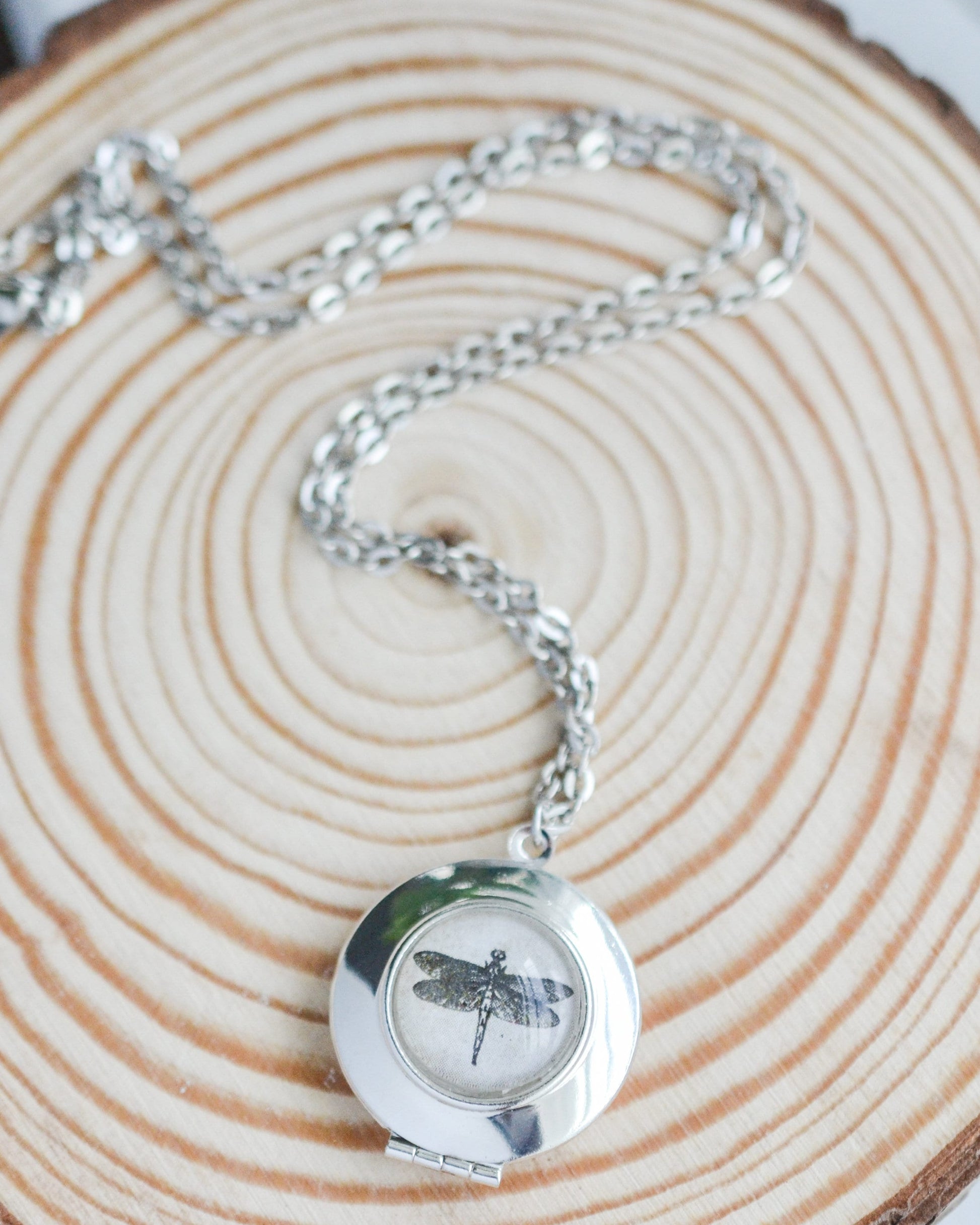 Silver necklace with a dragonfly pendant on a wooden surface