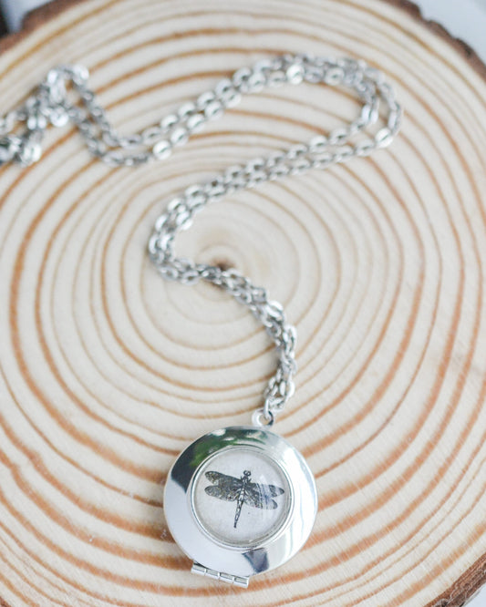 Silver necklace with a dragonfly pendant on a wooden surface