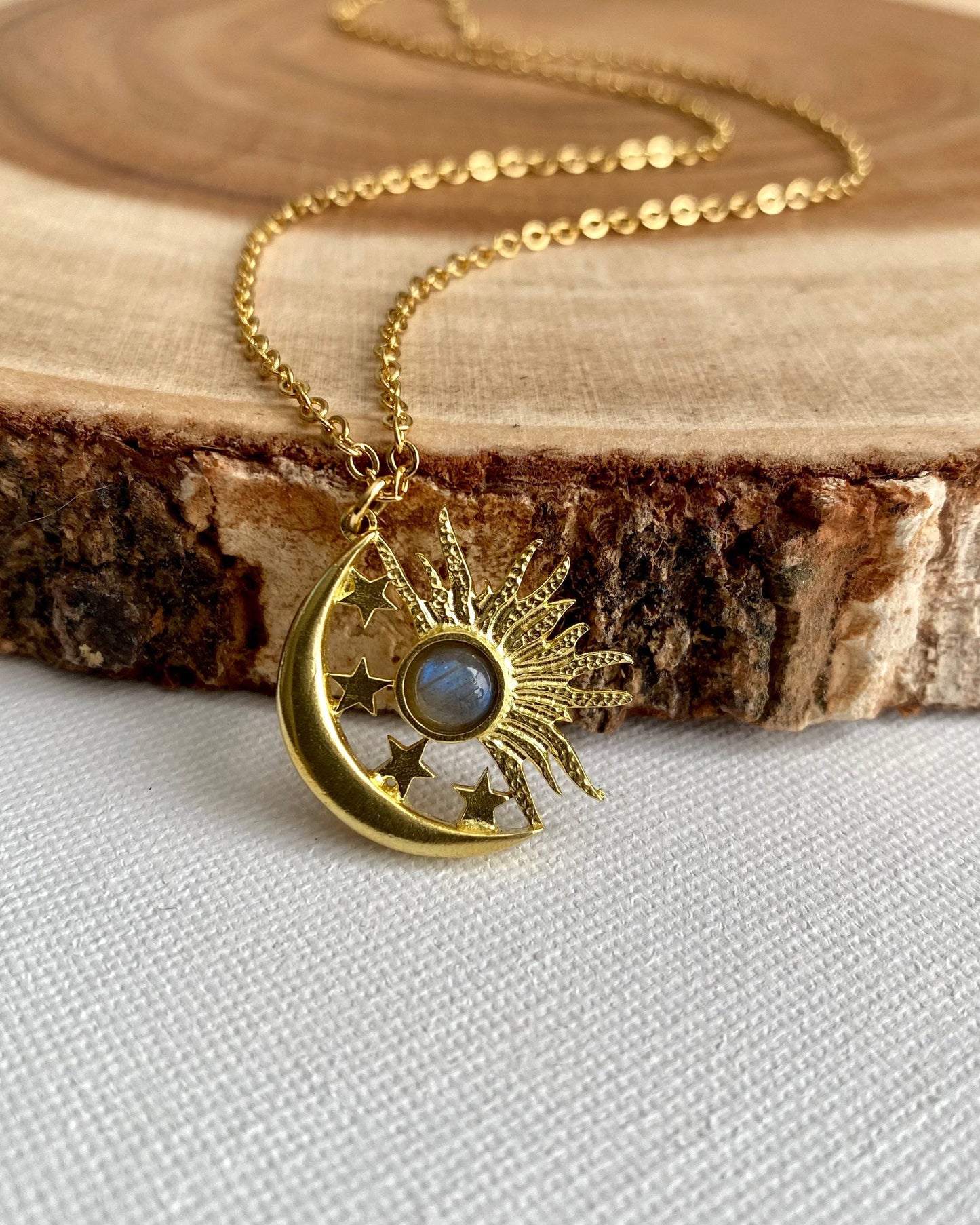 Gold necklace with a moon and star pendant on a wooden surface
