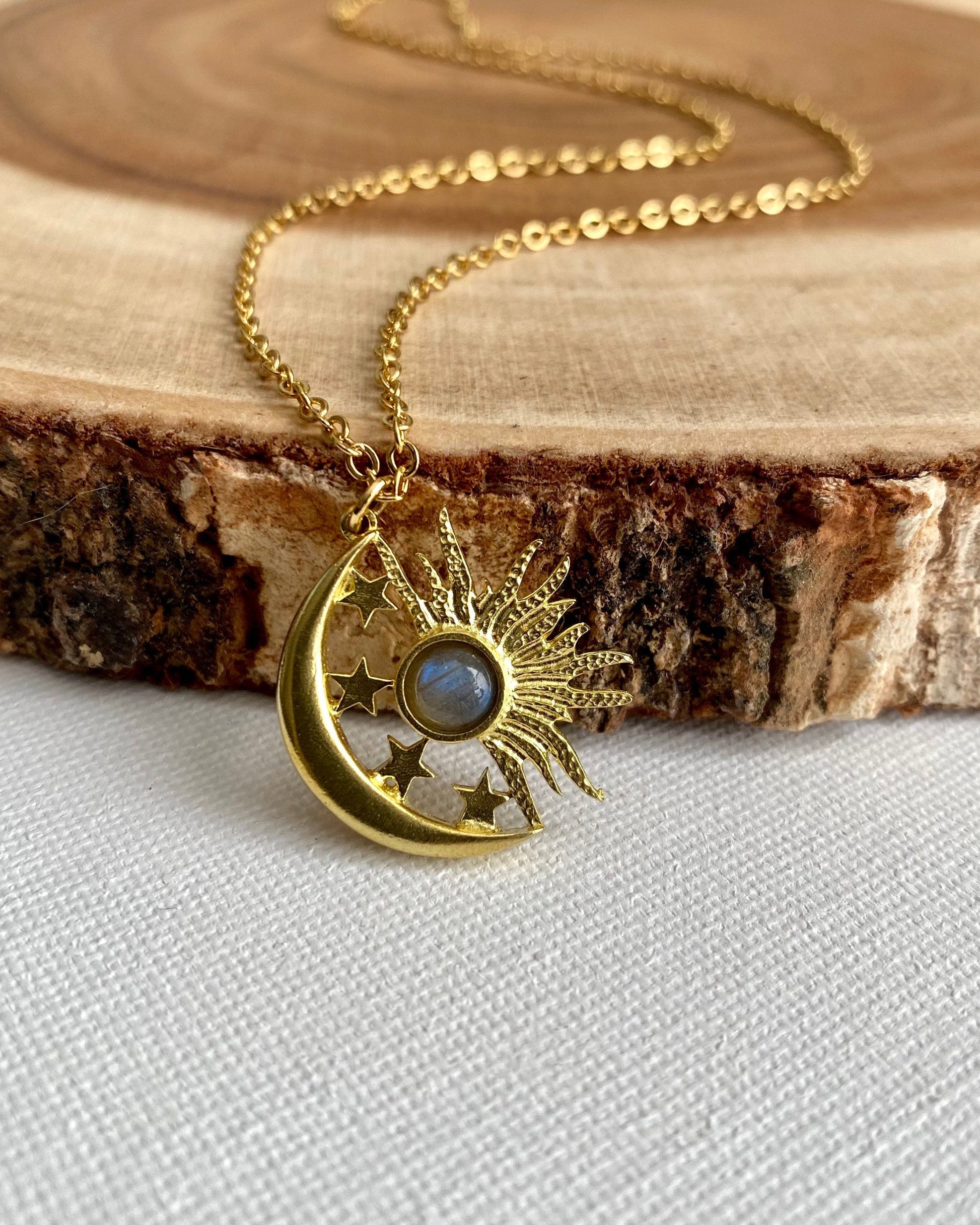 Gold necklace with a moon and star pendant on a wooden surface