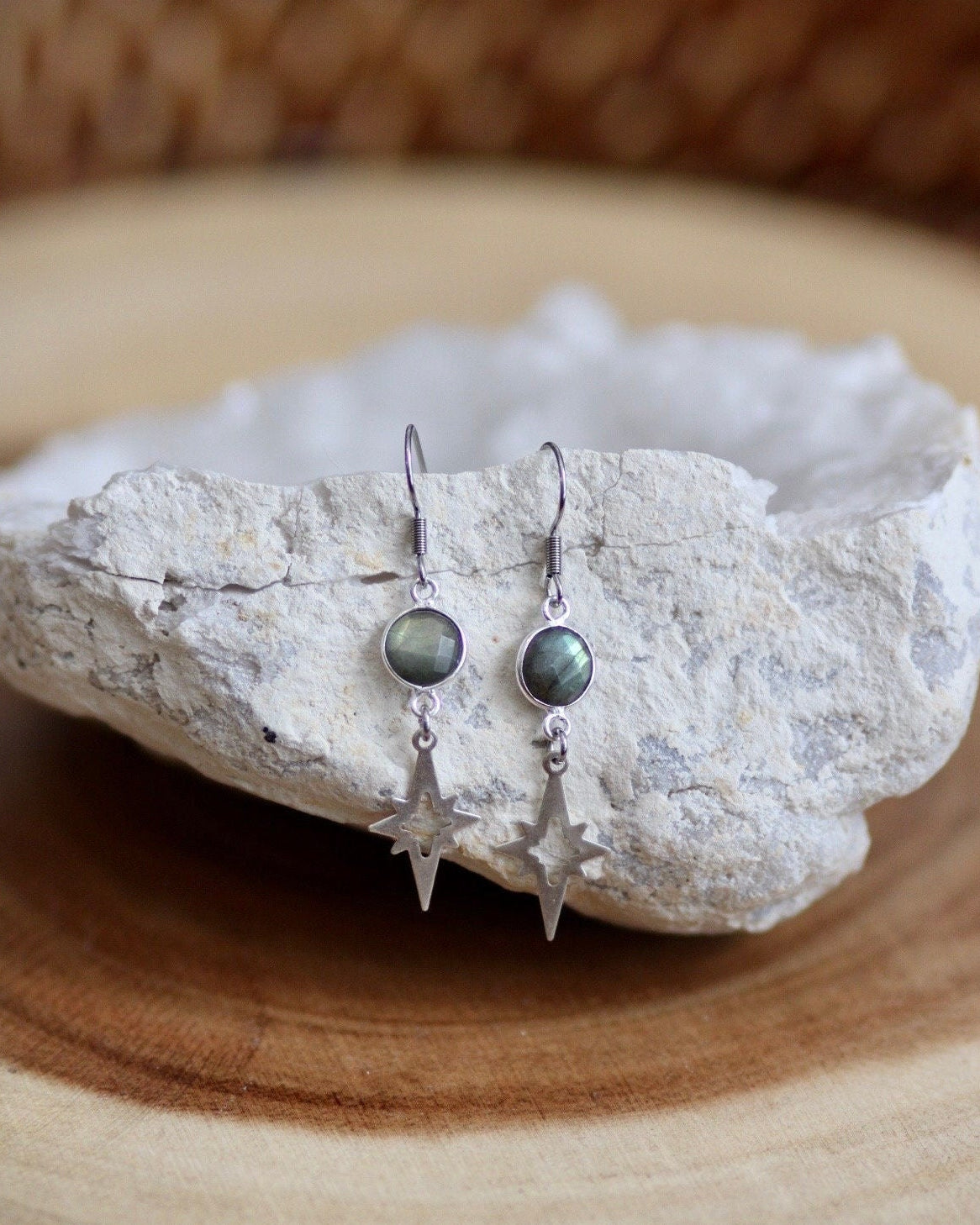 Pair of earrings with green gemstones on a white stone surface.