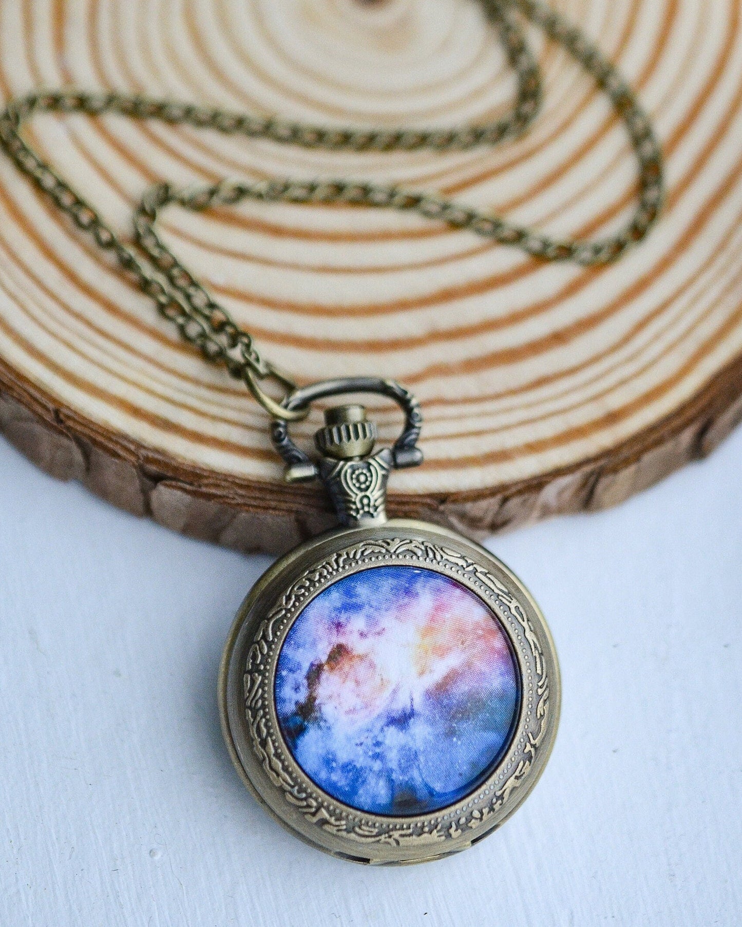Necklace with a pendant featuring a colorful galaxy design on a wooden surface.