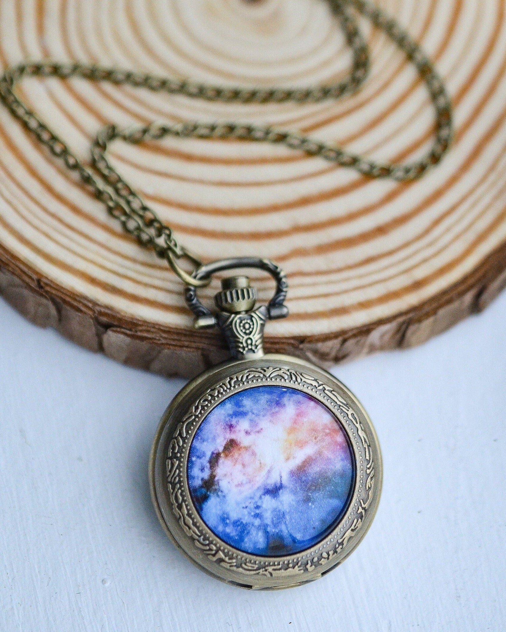 Necklace with a pendant featuring a colorful galaxy design on a wooden surface.