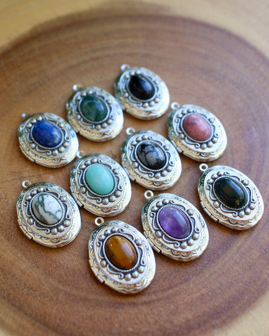 Set of silver locket pendants with colorful gemstones on a wooden surface