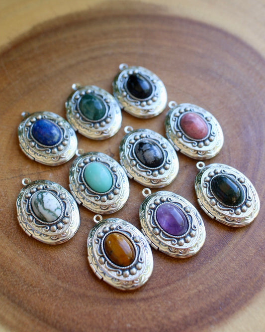 Set of silver locket pendants with colorful gemstones on a wooden surface