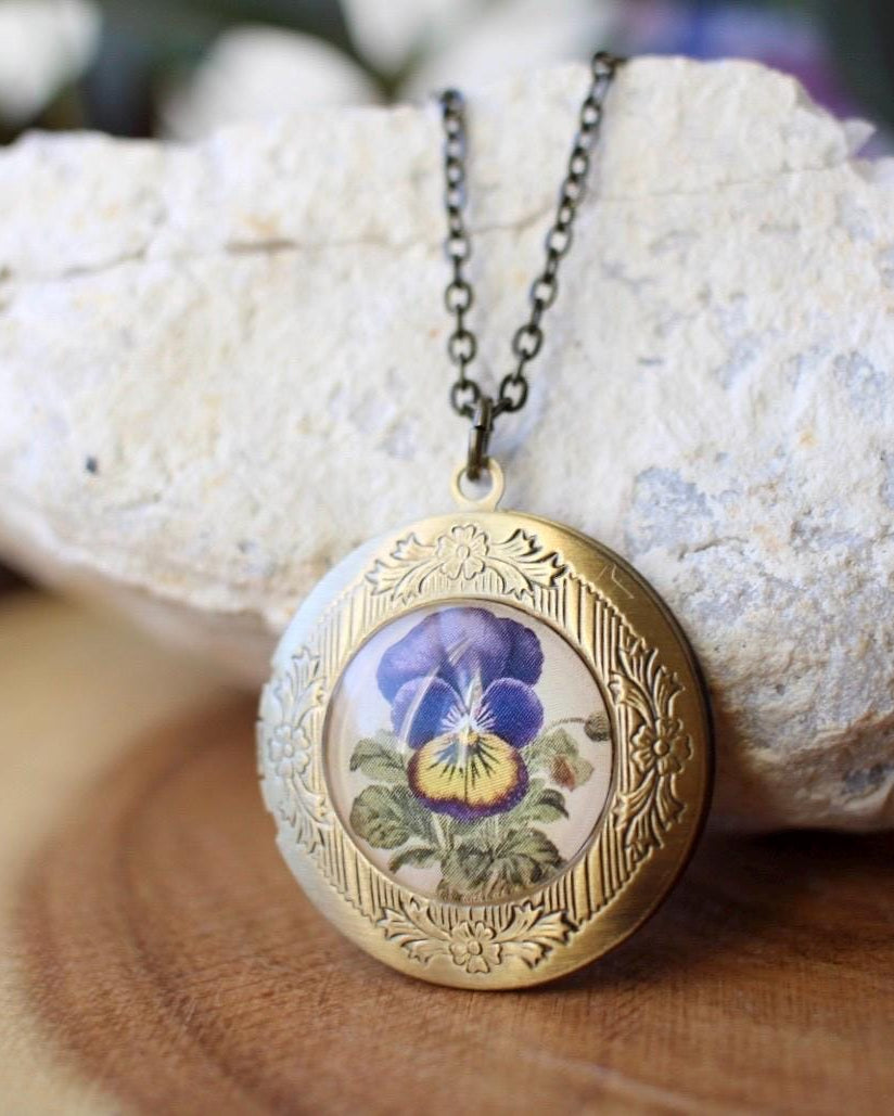 Brass locket with floral design on a rock