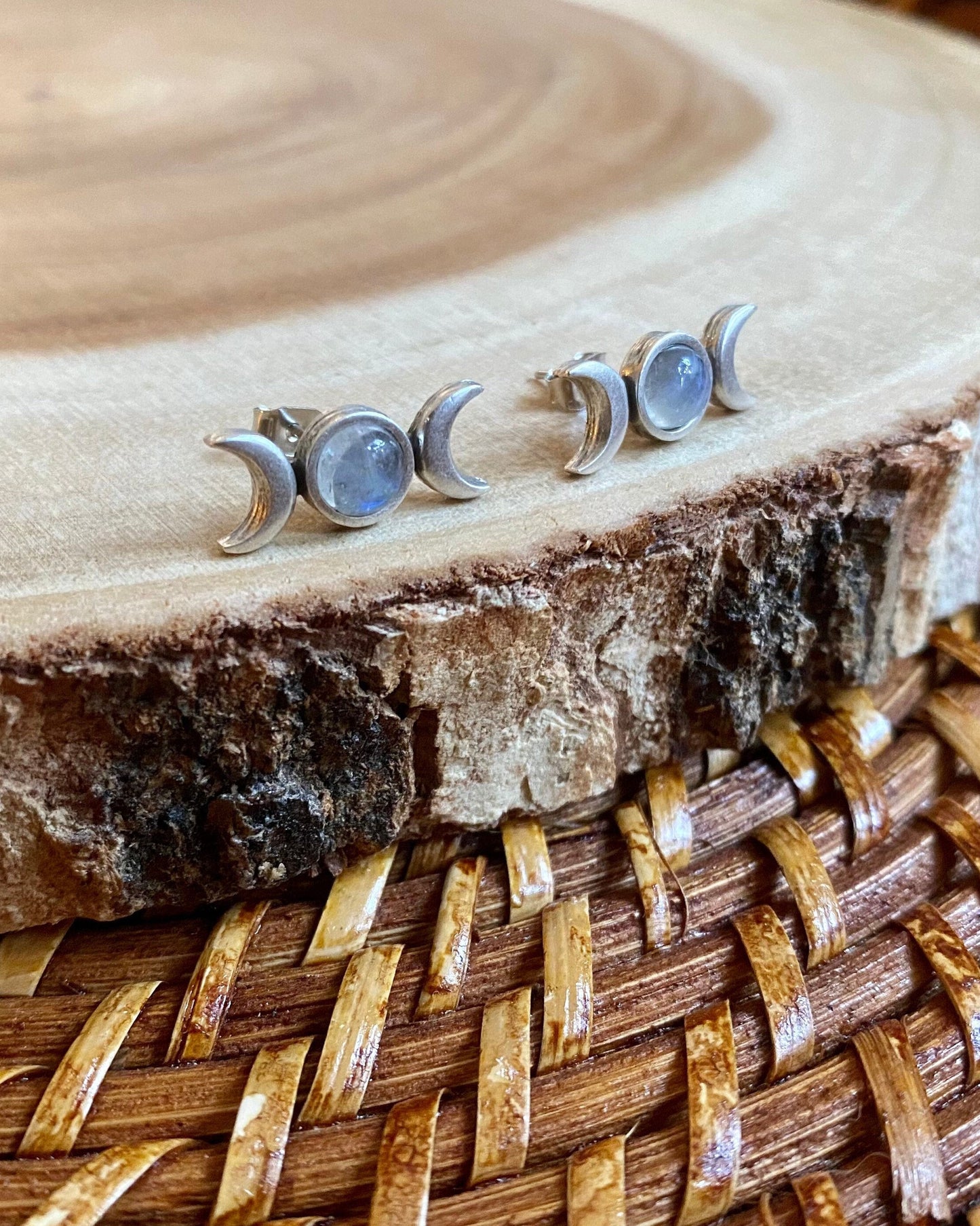 Set of silver moon phase earrings on a wooden surface