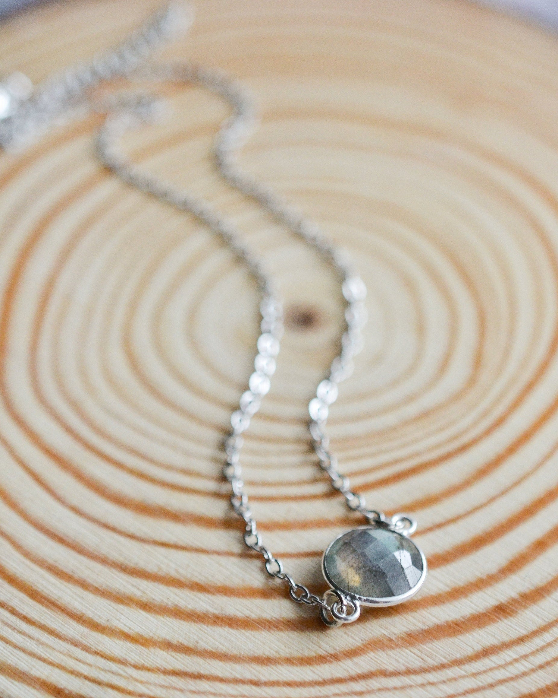 Silver necklace with a round gemstone on a wooden surface