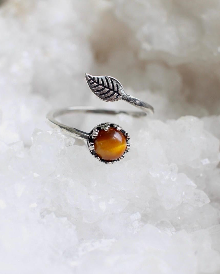 Silver ring with a brown stone on a white crystal background
