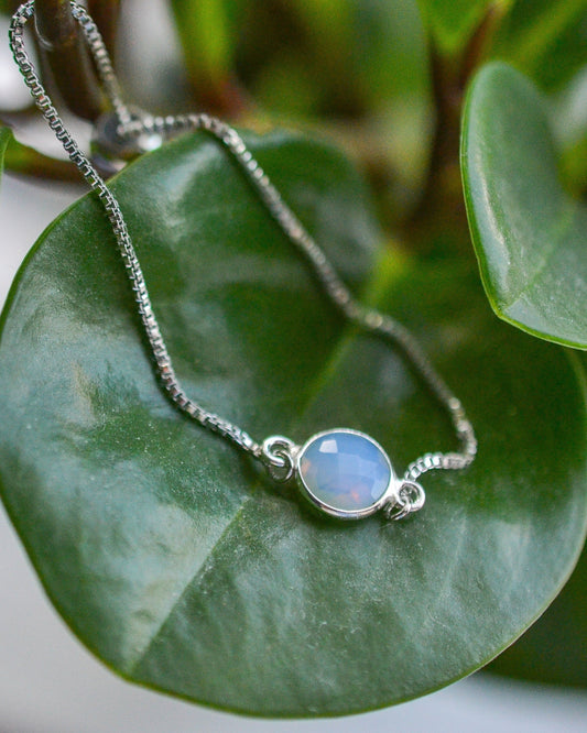 Silver bracelet with a opal stone on green leaves
