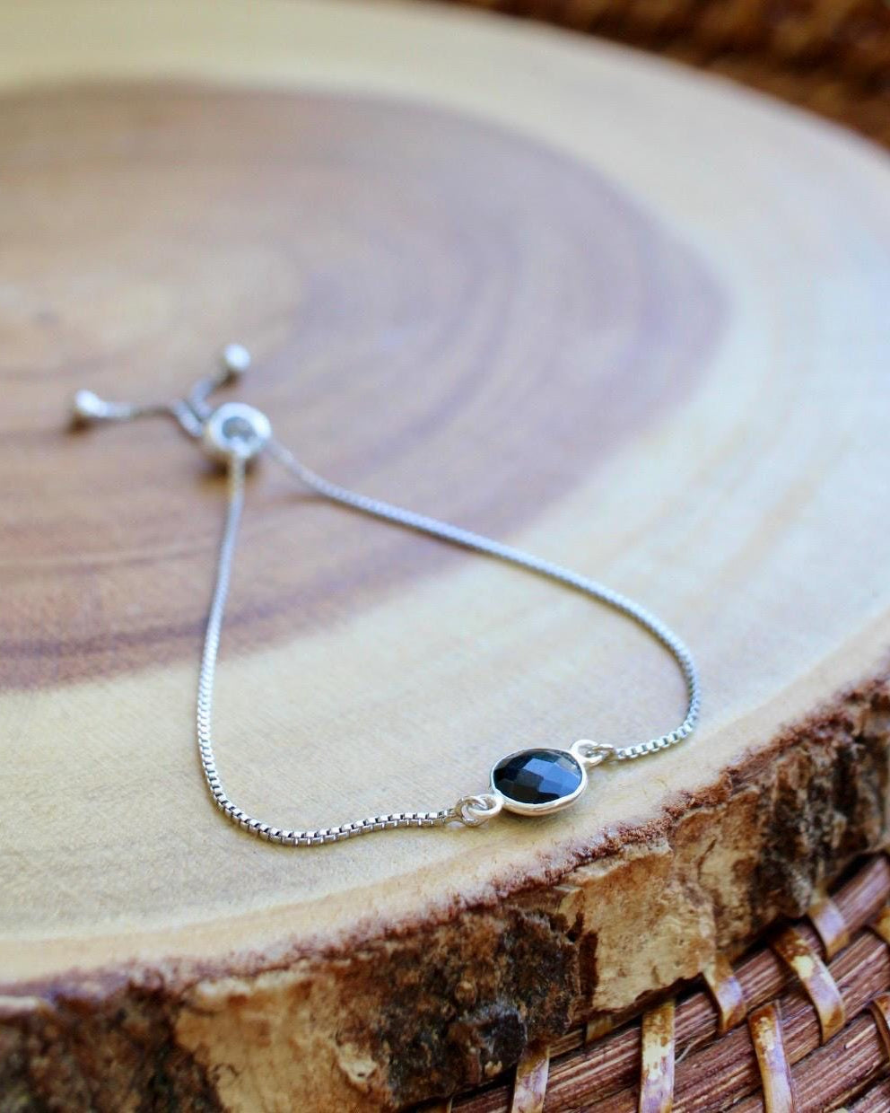Silver bracelet with a black stone on a wooden surface