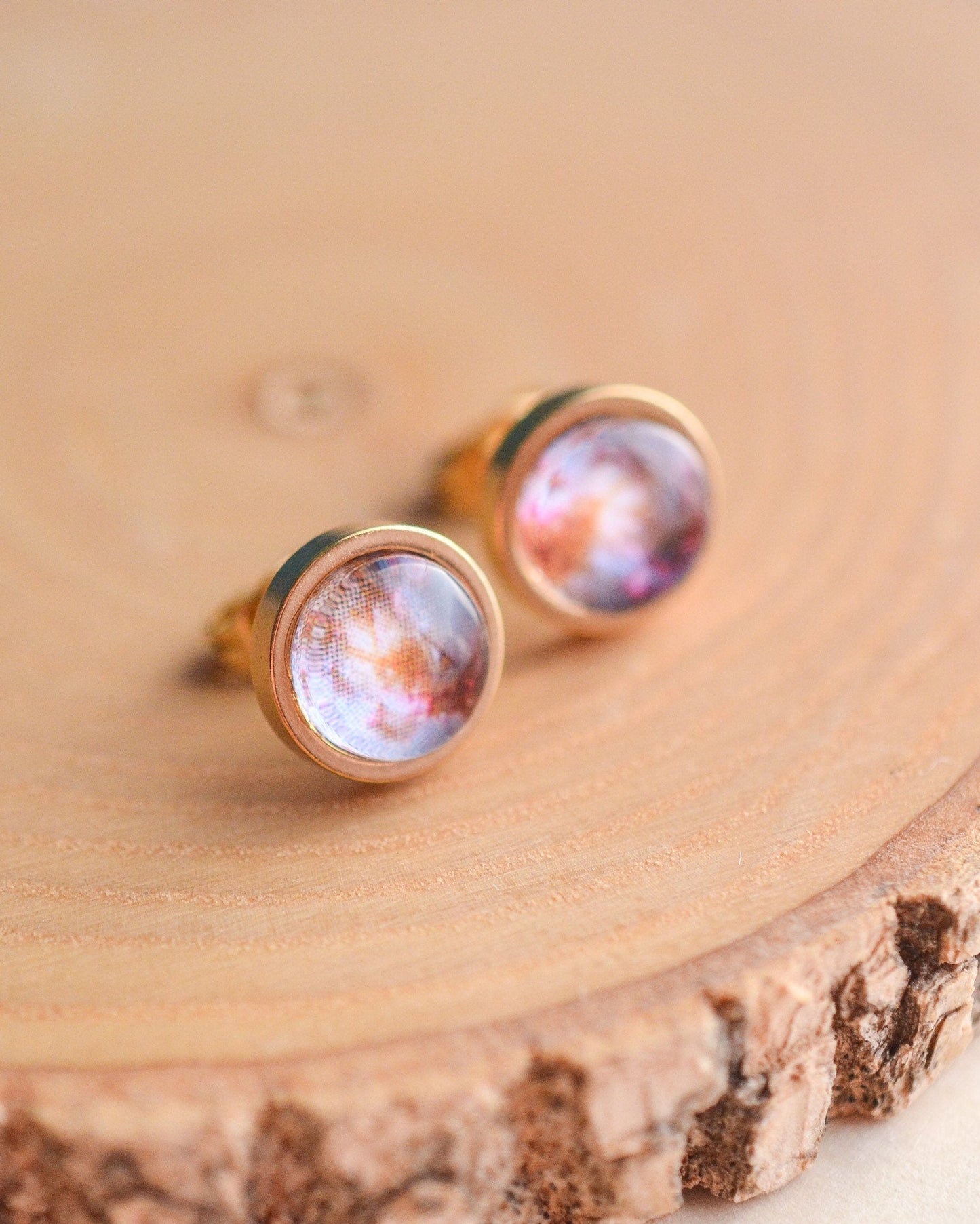 Pair of earrings with galaxy design on a wooden surface