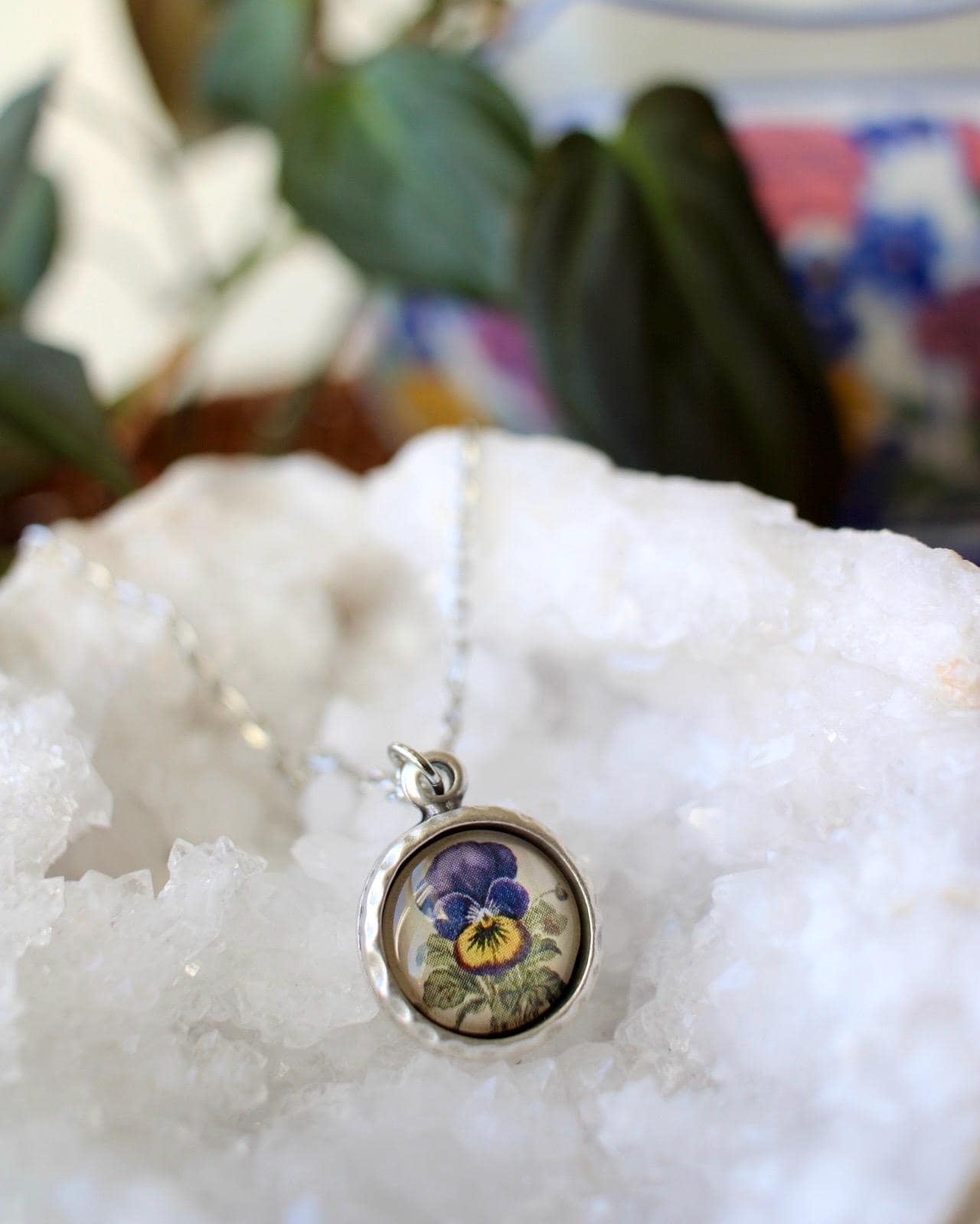 Necklace with a pendant featuring a floral design on a white stone surface.