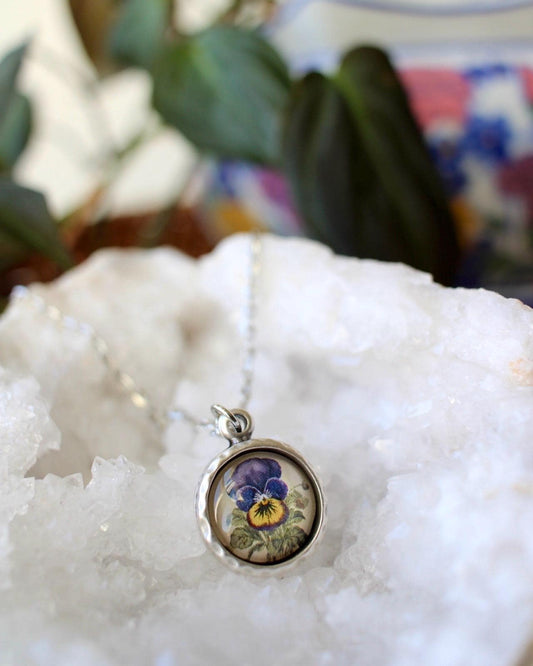 Necklace with a pendant featuring a floral design on a white stone surface.
