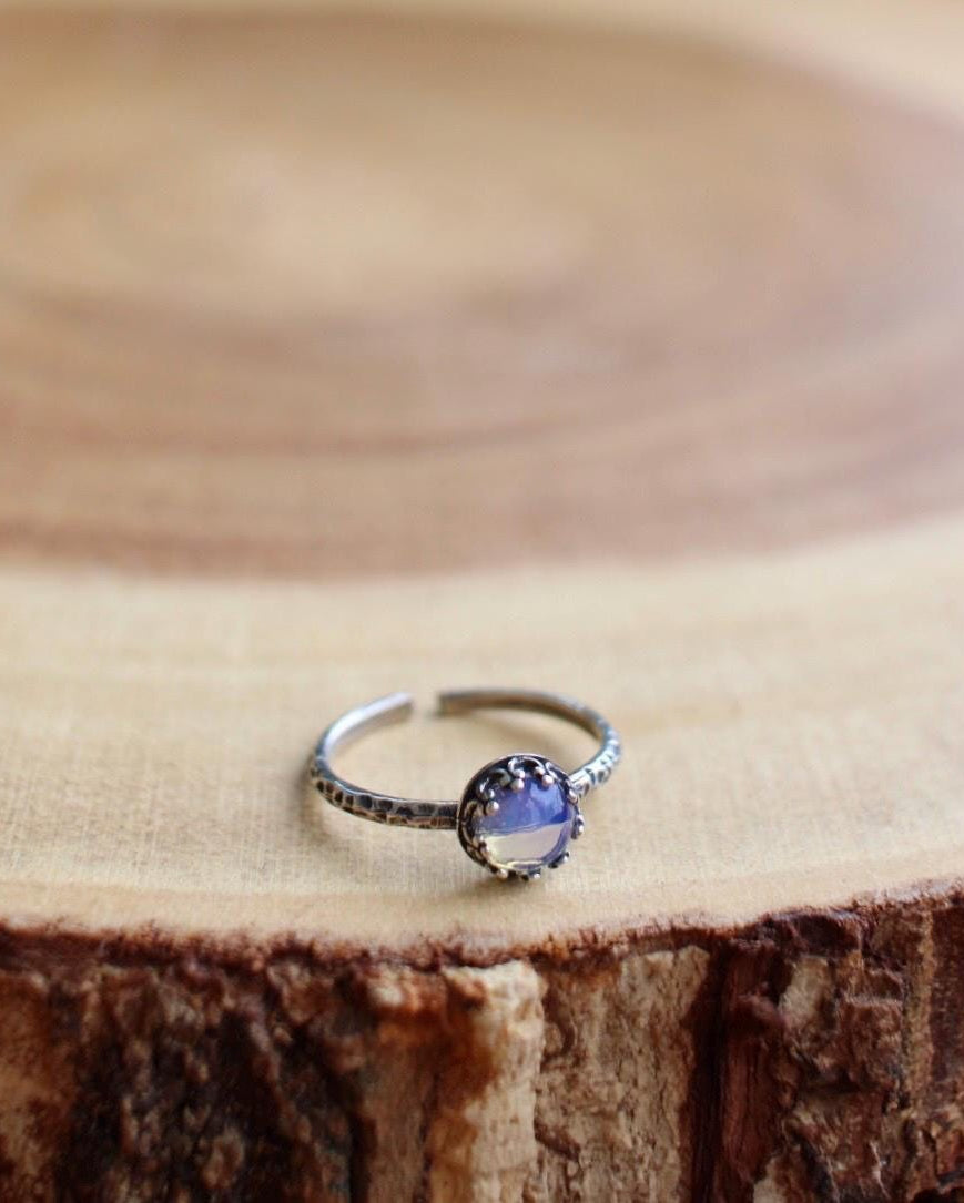 Silver ring with a clear blue gemstone on a wooden surface