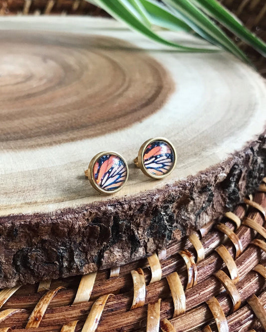 Pair of earrings with a butterfly wing design on a wooden surface
