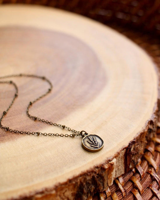 Necklace with a round lavender flower pendant on a wooden surface