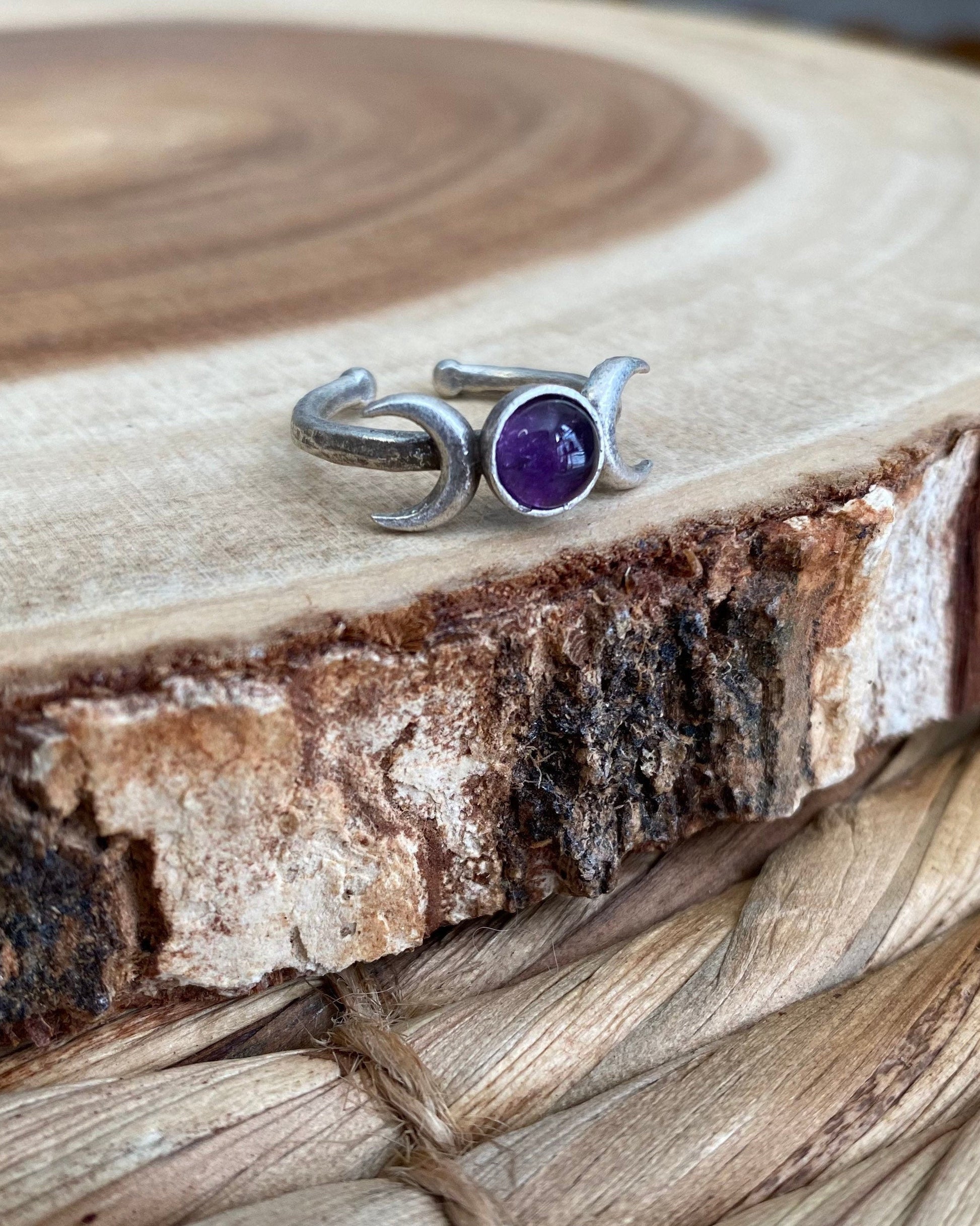 Silver ring with a purple gemstone on a wooden surface