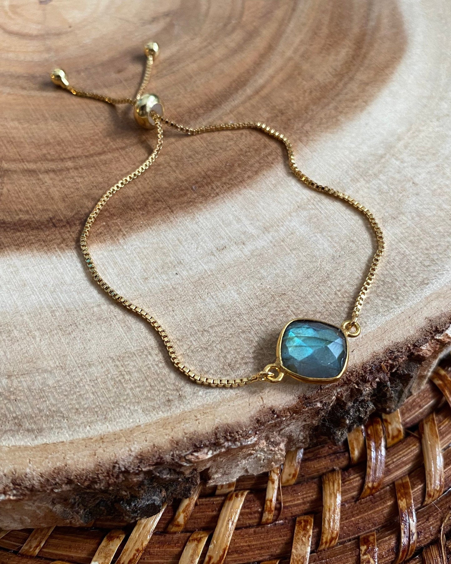 Gold bracelet with a blue green gemstone on a wooden surface