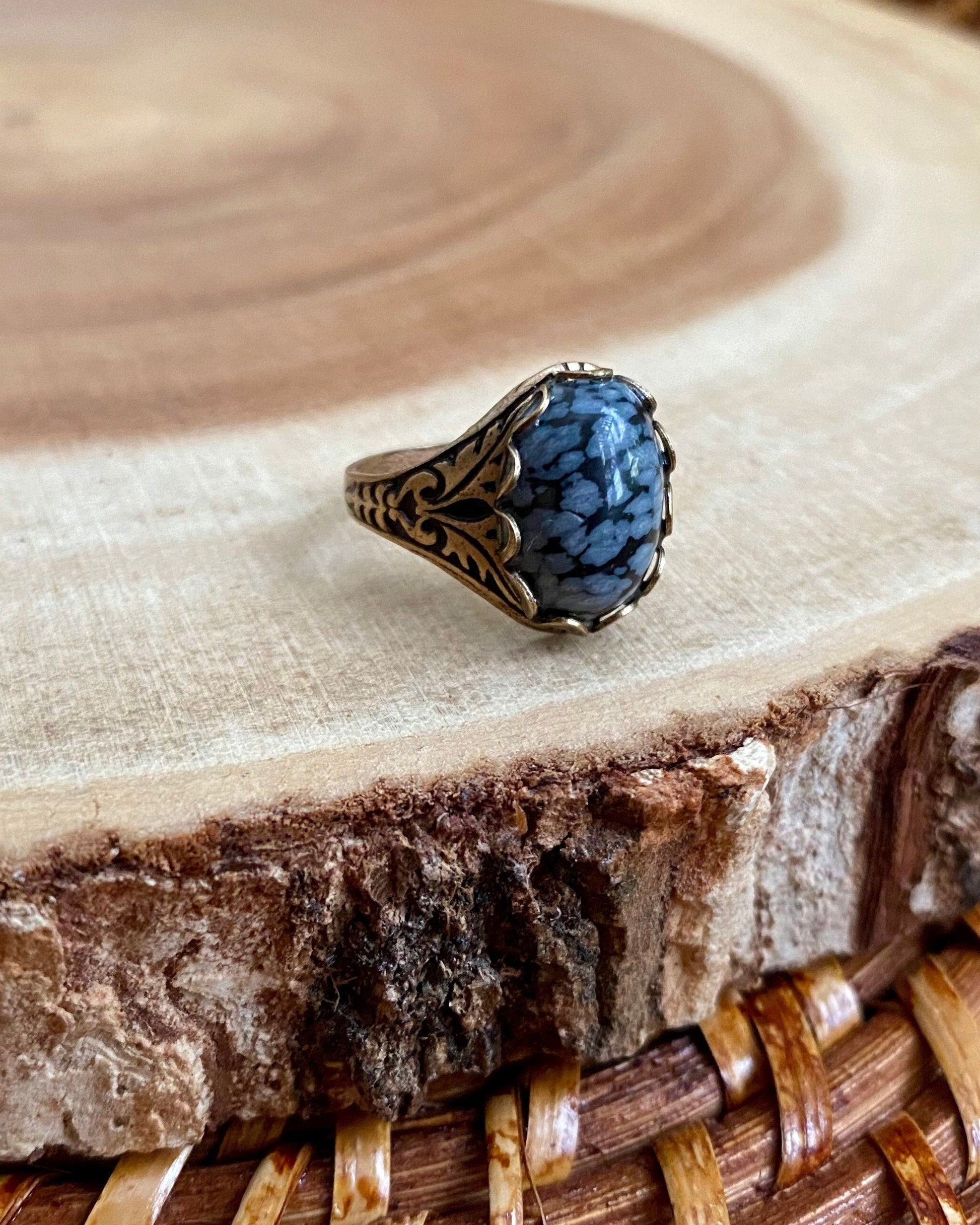 Ring with grey and black stone on a wooden surface