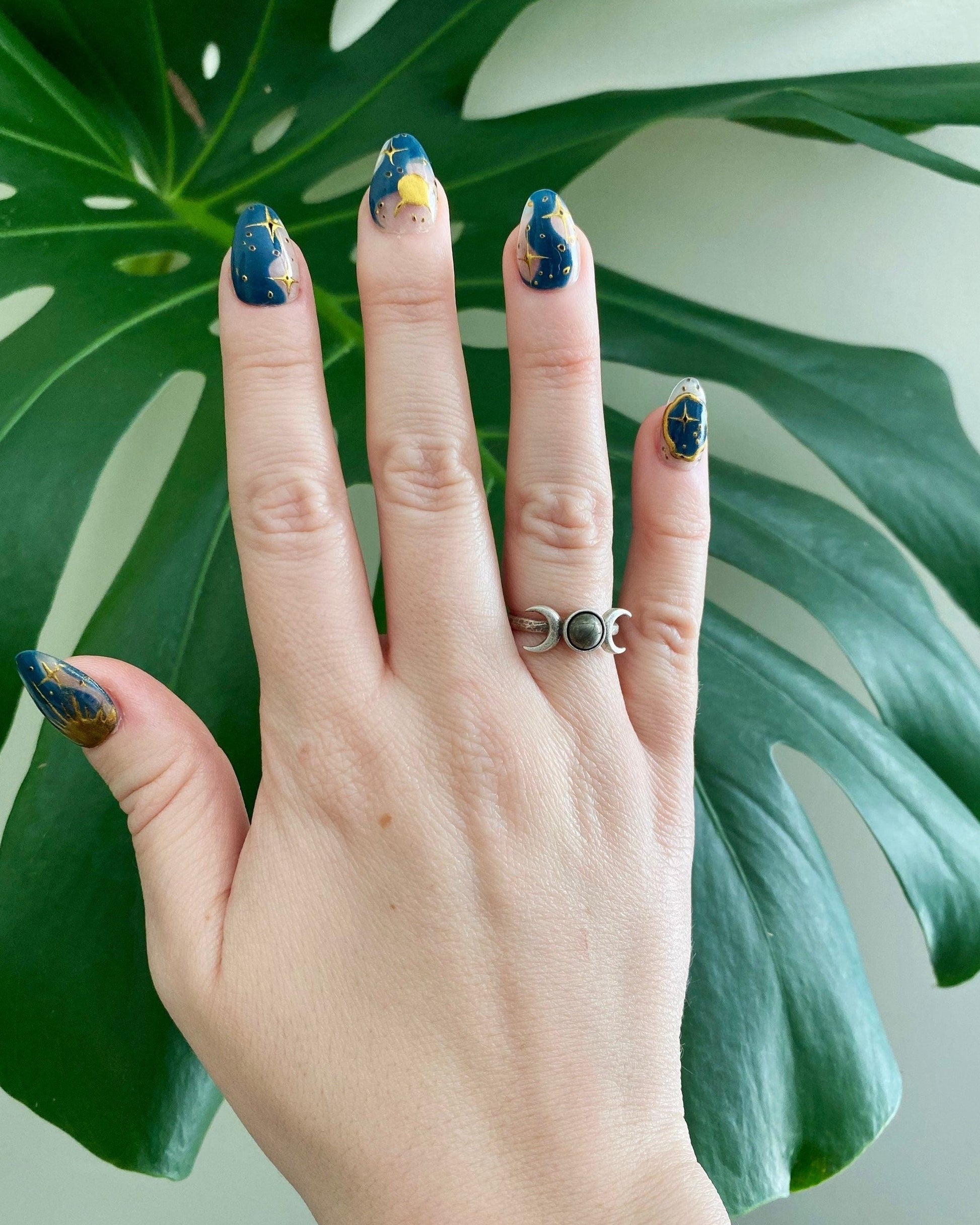Pyrite triple moon ring on a hand with galaxy nails