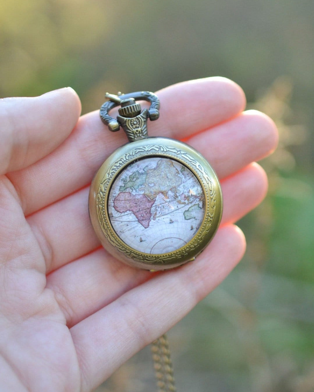 Pocket watch with a map imagine beind held in a hand