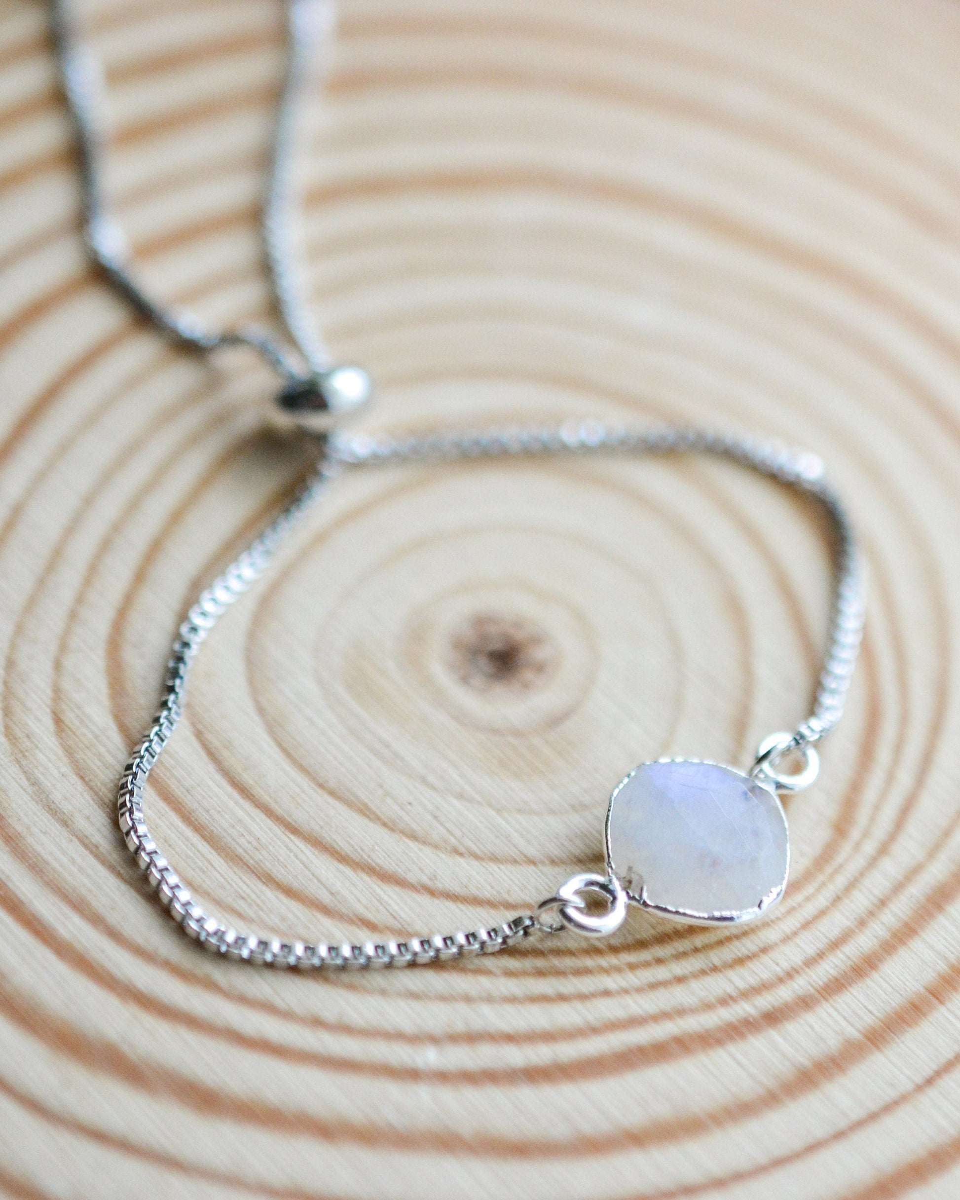 Silver bracelet with a moonstone pendant on a wooden surface