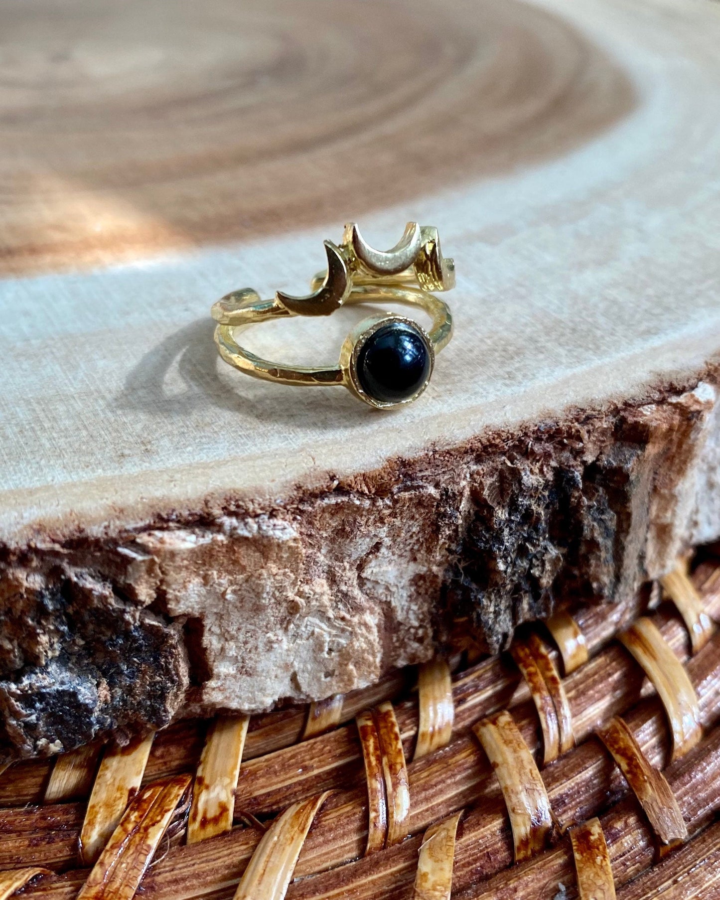Gold ring with a black stone on a wooden surface