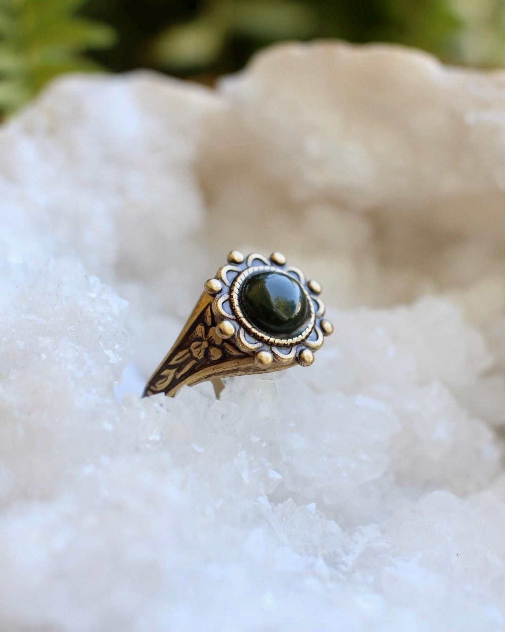 Bronze ring with a green gemstone on a white crystal background