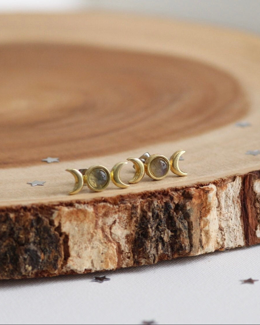 Set of gold moon phase earrings on a wooden surface