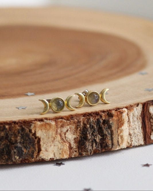 Set of gold moon phase earrings on a wooden surface