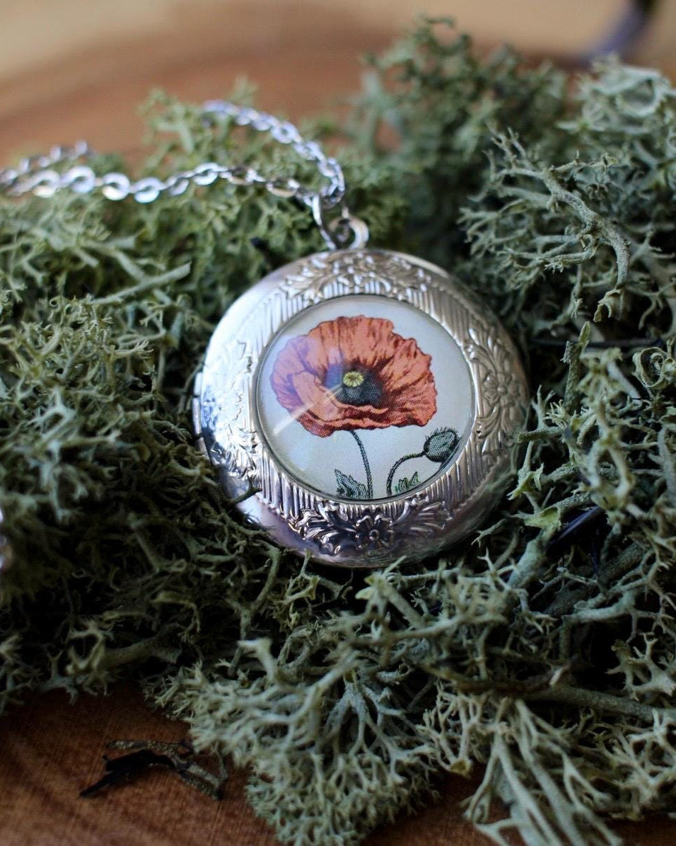 Necklace with a pendant featuring a poppy flower design on a bed of green moss.